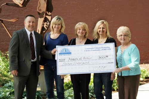 Julie Miller, Anita Farrar and Stephanie Woodworth, from Angels of Action, are presented with a check by MCCF Board members Mike Mohnke and Yo Bellingar for $3,000 to help with their “Backpack Blessings” program.