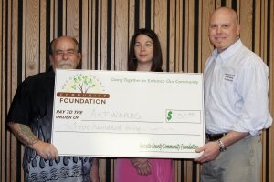 Board member Dr. Tony Foster presents representatives from Artworks a grant for $350.