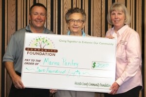Isabel Kempton, from Manna Pantry, is presented a grant for $250 from board members Mike Mohnke and Debbie Patterson.