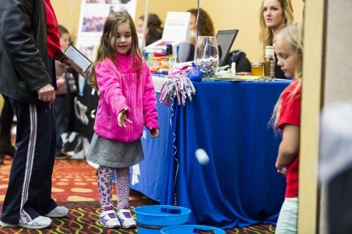 TOSS: Abigail Harrower tosses a ball into one of the buckets in front of the Angels of Action booth at the Match Day 2015 event at the Holiday Inn on Tuesday. (Pioneer photo/Justin McKee)